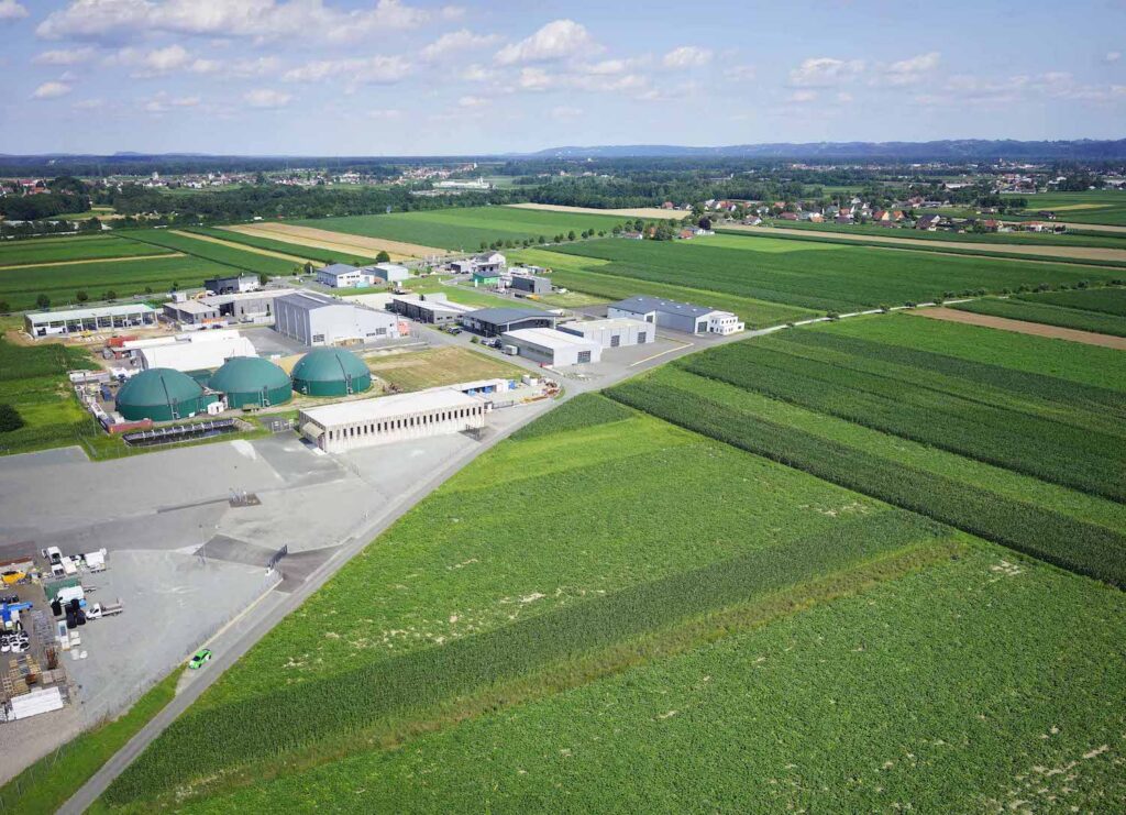 Landschaftsaufname einer Produktionsanlage die von grünen Feldern umgeben ist