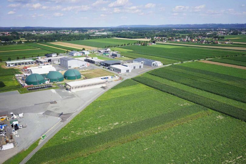 Landschaftsaufname einer Produktionsanlage die von grünen Feldern umgeben ist