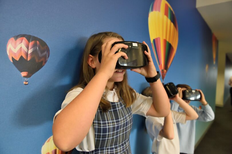 Mädchen probiert in ihrem Kinderzimmer eine VR-Brille aus.