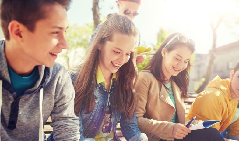 3 junge Menschen sitzen in der Sonne und lachen