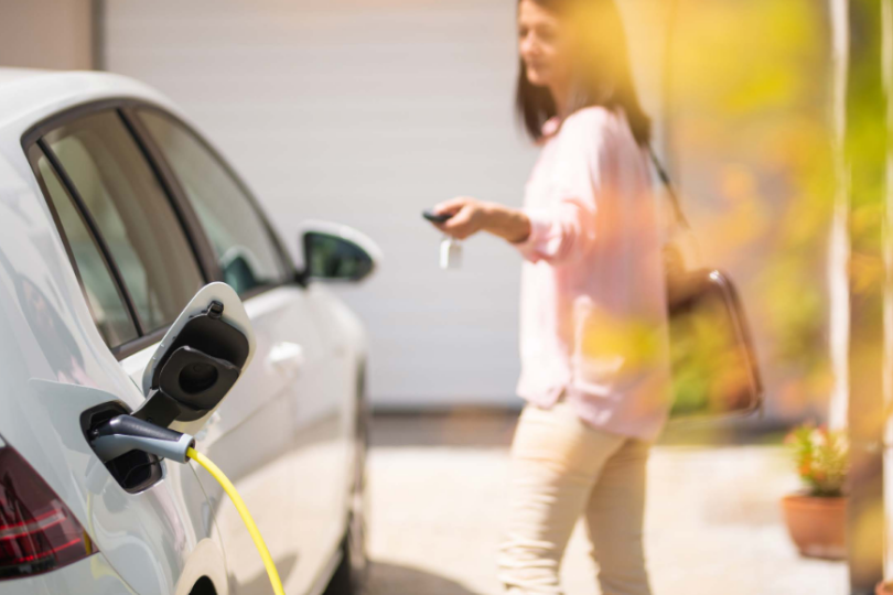 Frau vor einem Elektroauto.