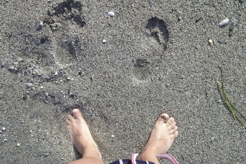 Füße im Sand und Fußabdrücke.