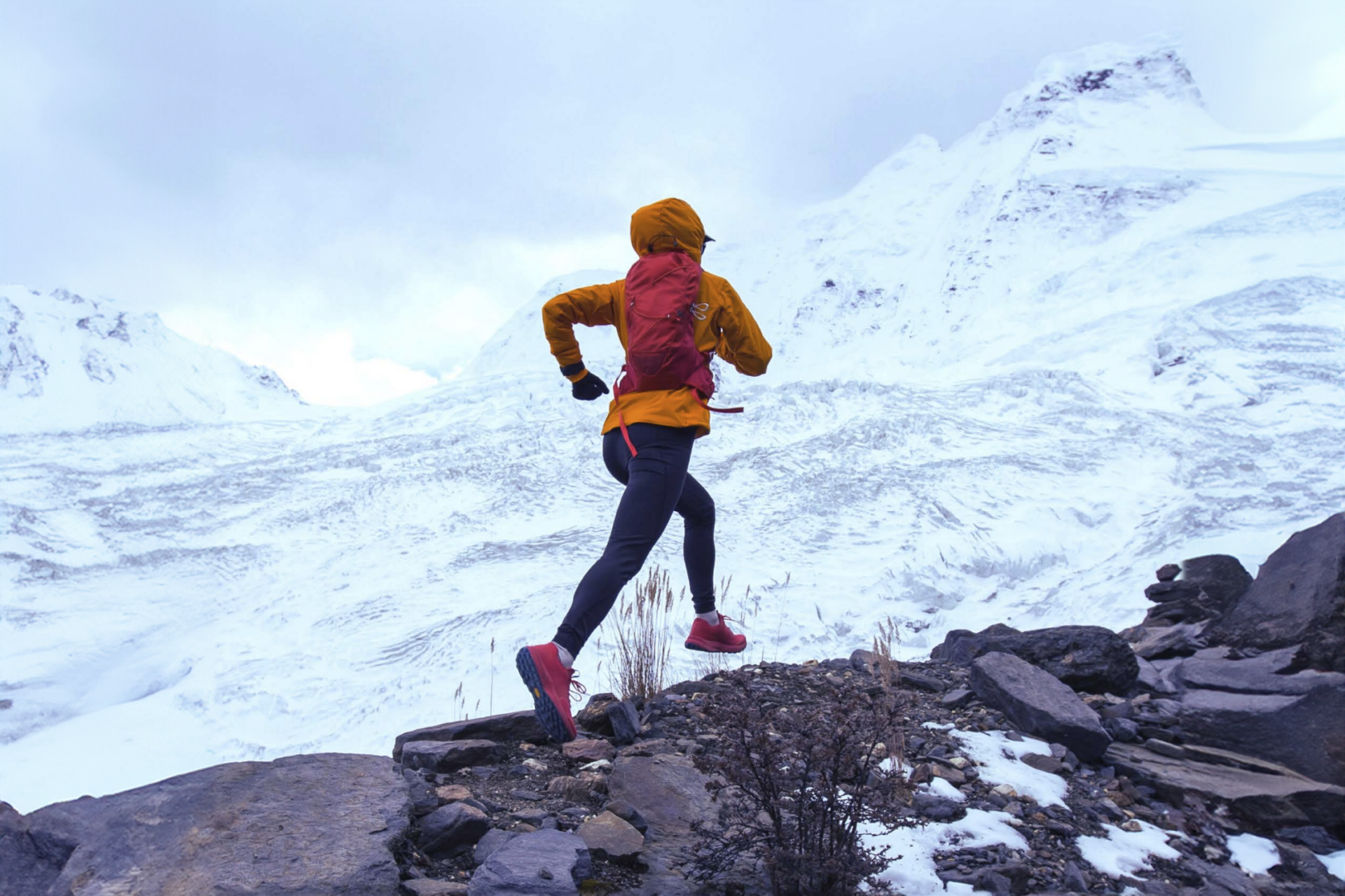 Frau in Winterlandschaft, die auf einem Berg hochläuft.