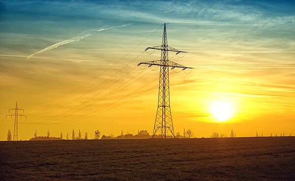 Ein Strommast vor aufgehender Sonne.