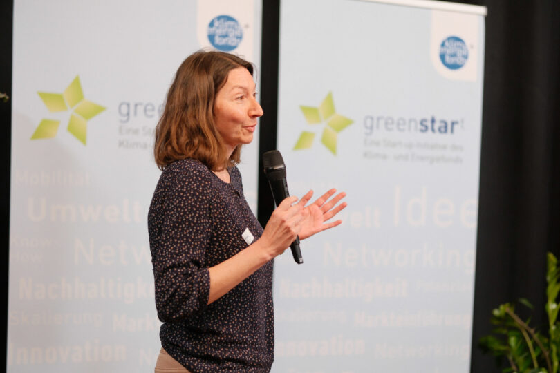 Karin Föttinger mit Mikrofon auf einer Bühne im Rahmen des Greenstart Förderprogramms.