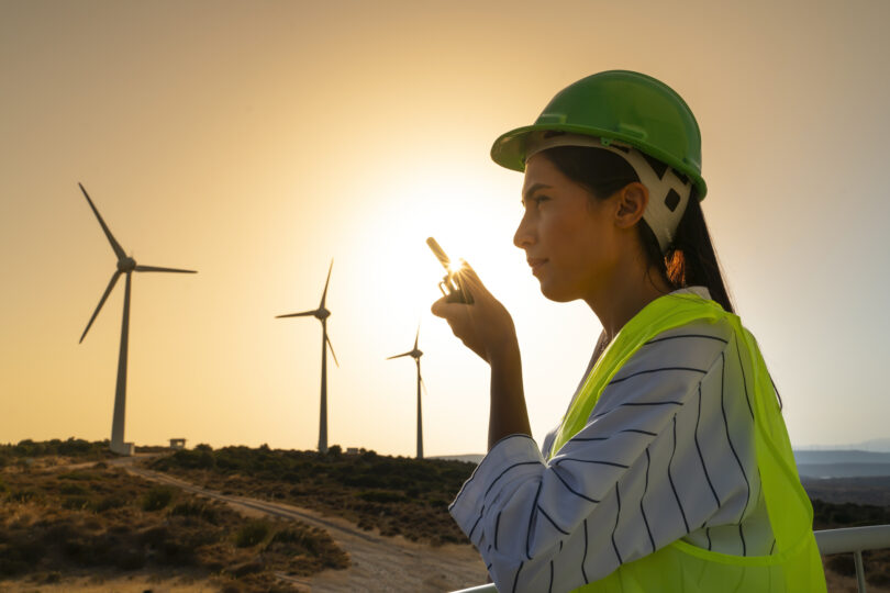 Junge Wartungstechnikerin bei der Arbeit in einer Windkraftanlage bei Sonnenuntergang.