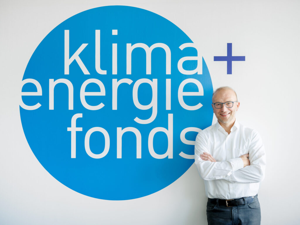 Geschäftsführer Bernd Vogl vor dem Logo des Klima- und Energiefonds.