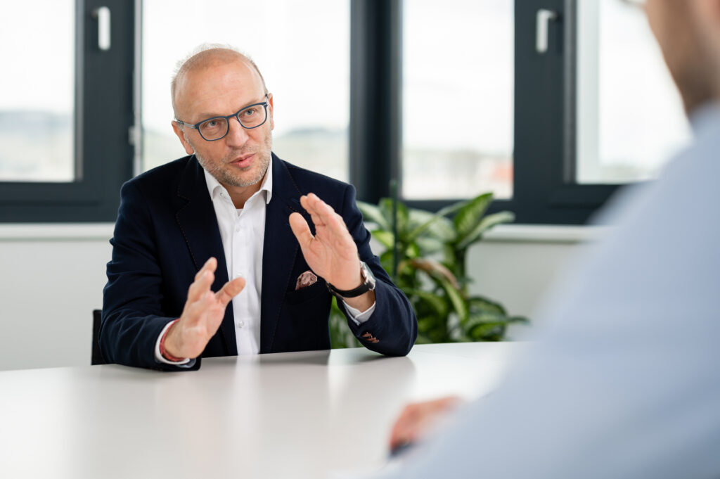 Geschäftsführer Bernd Vogl erklärt etwas am Tisch sitzend.