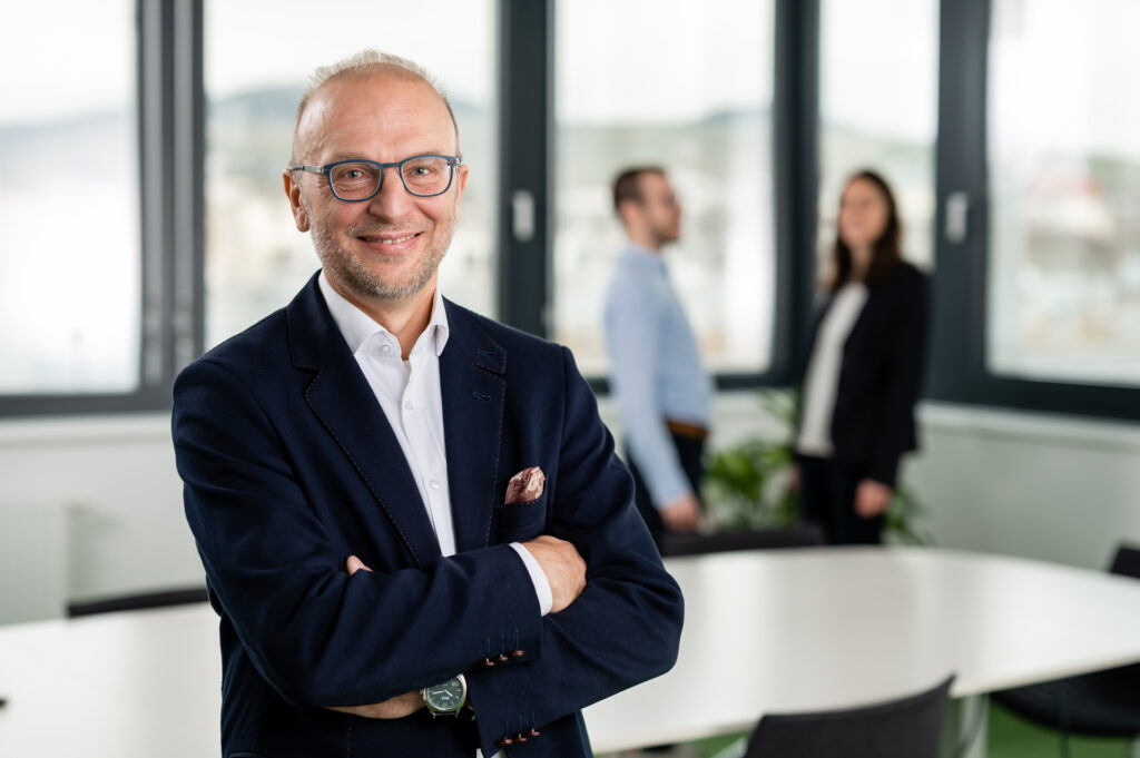 Geschäftsführer Bernd Vogl mit verschränkten Armen im Büro.