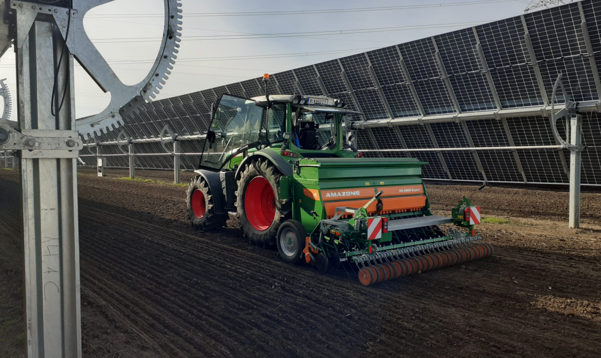 bewegliche Agri PV Anlage mit einem Traktor in der Mitte zwischen zwei PV Anlagen auf dem Feld