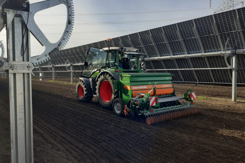 bewegliche Agri PV Anlage mit einem Traktor in der Mitte zwischen zwei PV Anlagen auf dem Feld