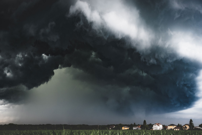 Panoramablick auf dunkle Gewitterwolken über einer ländlichen Landschaft mit Häusern.