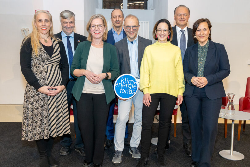 Eine Gruppe von Menschen steht zusammen mit einem Schild „Klima und Energie Fonds“.