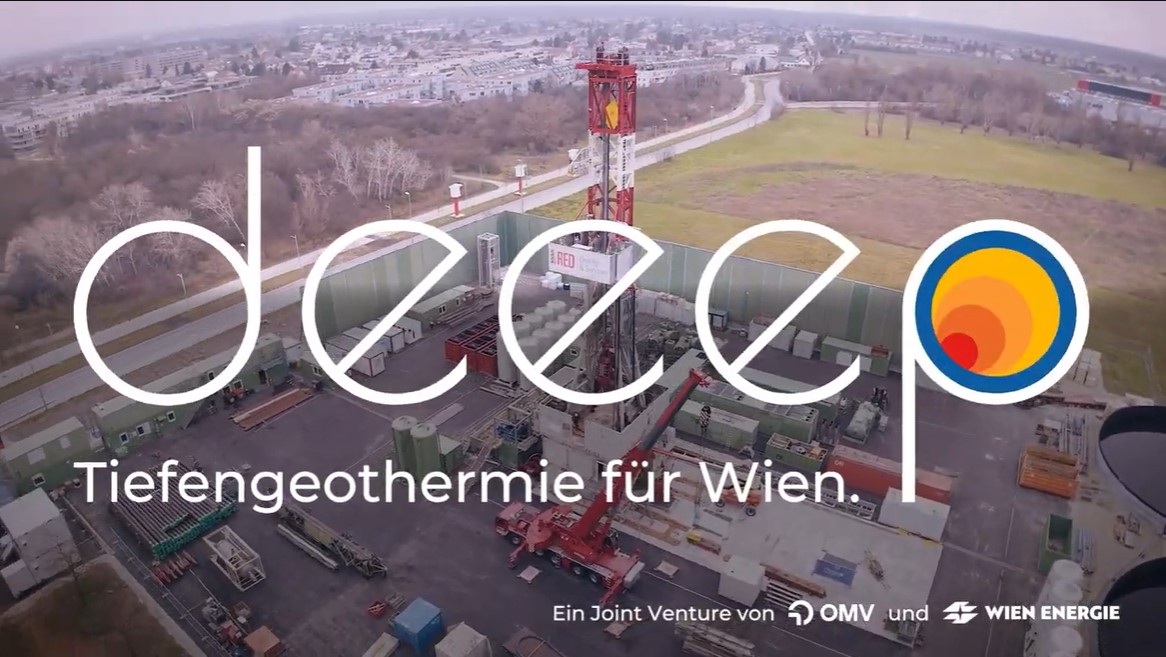 Luftaufnahme einer Geothermie-Bohranlage in Wien mit einem großen roten Bohrturm in der Mitte. Der Schriftzug 