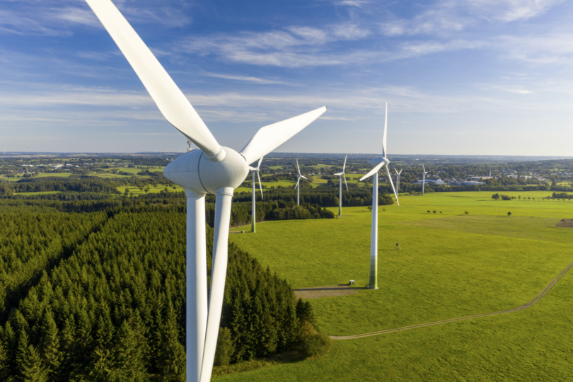 Luftaufnahme von Windturbinen in einer grünen Landschaft unter einem klaren Himmel.